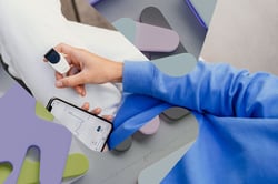 Nærbilde av hender som holder en fingermåler som viser resultatene i en mobilapp