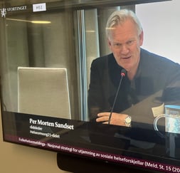 Mann med hvitt hår snakker i mikrofon